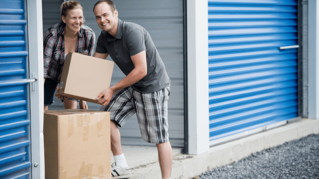 Couple holding moving boxes in front of a self storage unit while preparing for a move to Texarkana