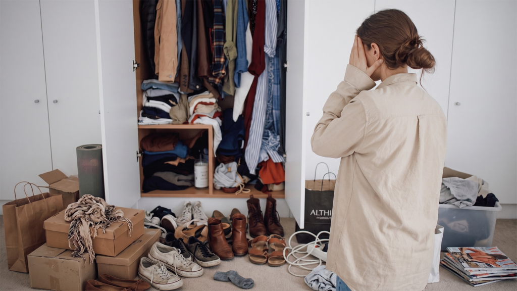 Woman stressed by a cluttered closet while looking for storage solutions for moms